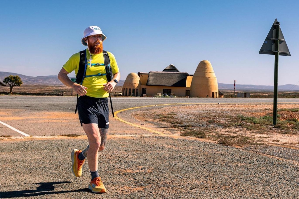 Russell Cook running beside a dirt track in a sunlit African savannah